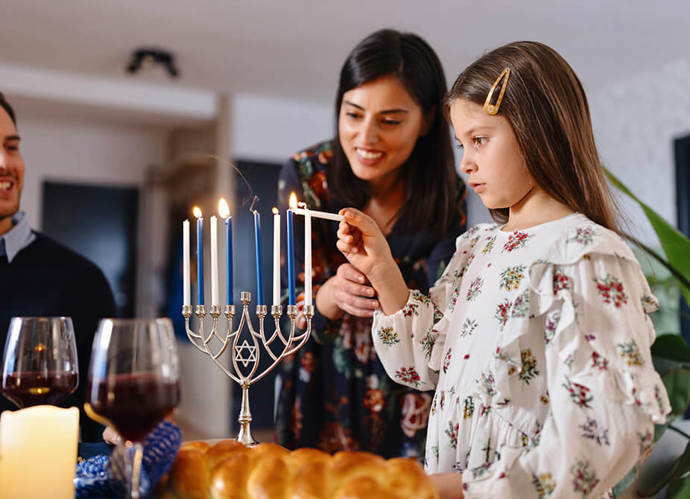 A young girl lighting Menorah at the dining table