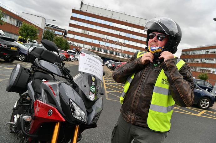 A Pick Up and delivery volunteer taking off his motorcycle helmet 