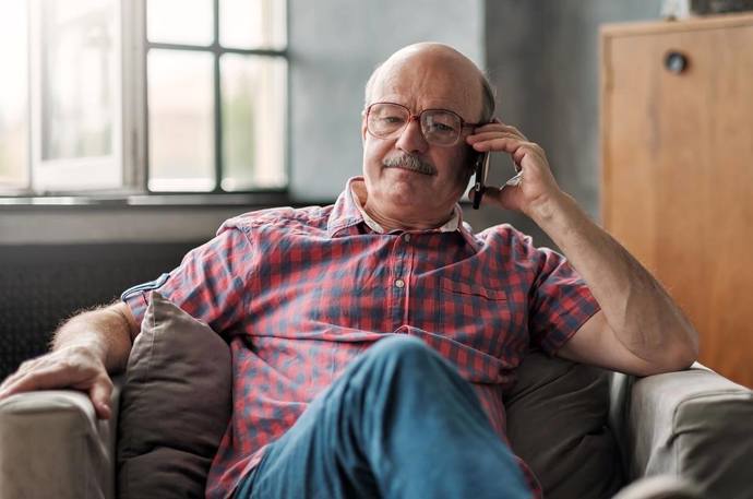 An older man looking concerned while talking on the phone 