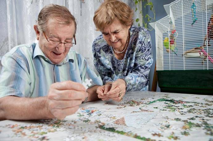 An older man and woman doing a jigsaw puzzle