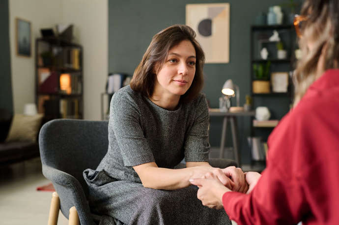 A woman holding the hands of another woman and smiling