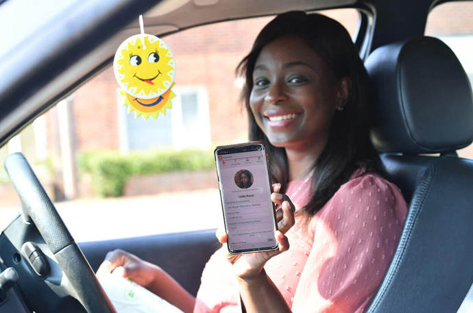 A younger volunteer in a car showing her mobile phone 