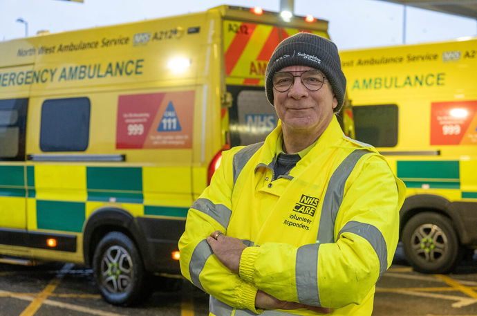 Ambulance Support Volunteer Phil in front a some parked ambulances 