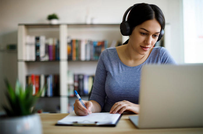 A woman looking at her computer with headphones on 