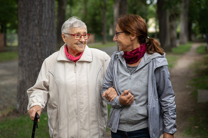 A volunteer supporting an older woman whilst out on a walk as part of Community Response activities