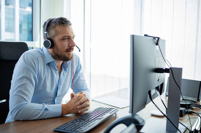 A proefessional looking at his computer with headphones on 