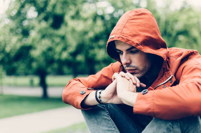 A young man wearing a hoodie looking concerned