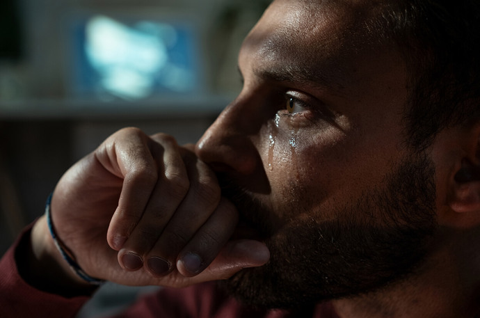 A close up image of a profile of a man with tears running down his face 