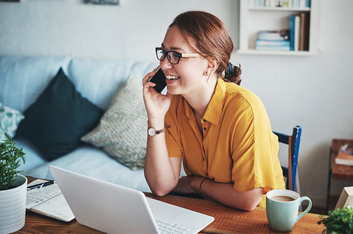 A young volunteer looking at her laptop while on the phone